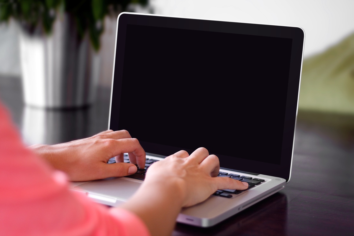 Hands typing on a laptop computer